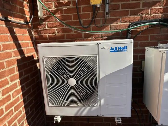 J&E Hall outdoor condensing unit on a brick wall